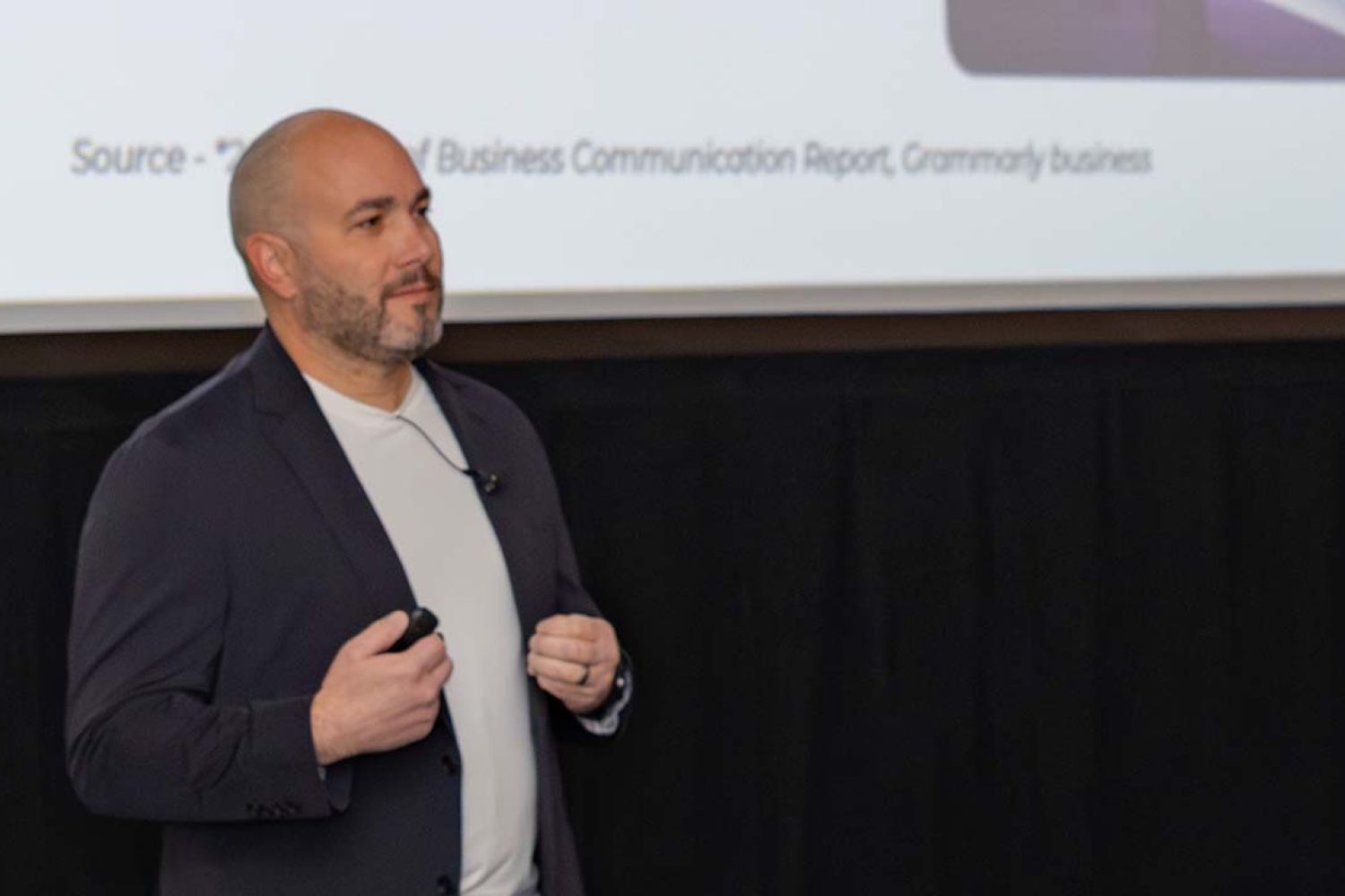 A man in a black suitcoat and white t shirt presenting
